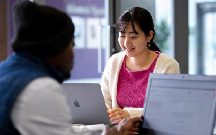 A student smiles as she looks at her laptop screen