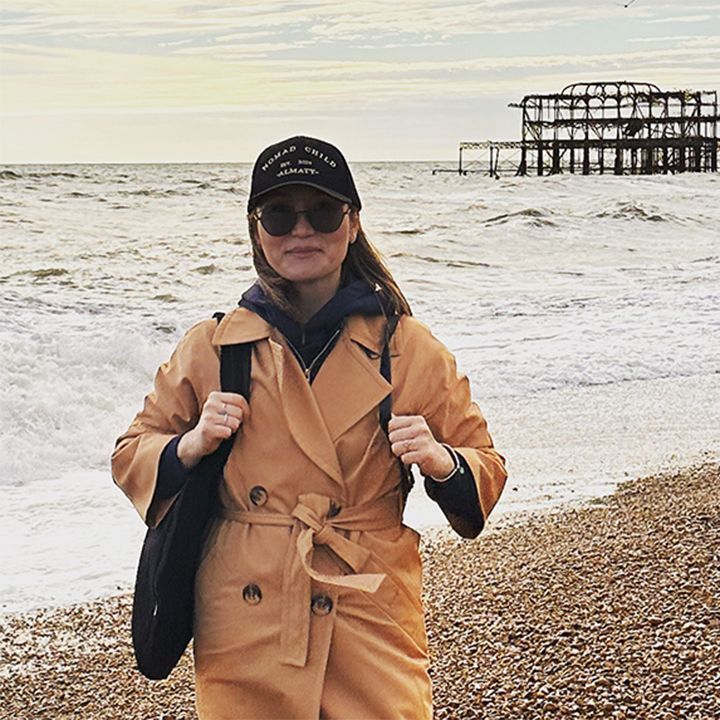A woman in a yellow coat stands on Brighton beach
