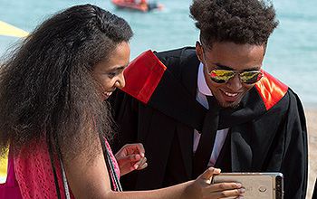 Two graduates look at a mobile phone screen