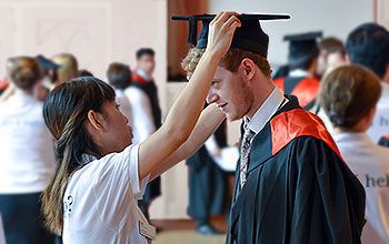 A student gets gowned in the robing room