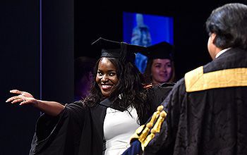 A student greets the Chancellor as she crosses the stage