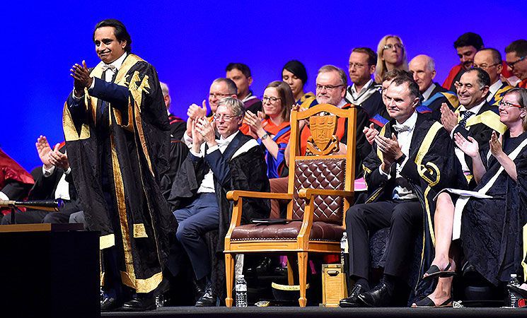 The Chancellor of Sussex leads applause from the stage during a ceremony