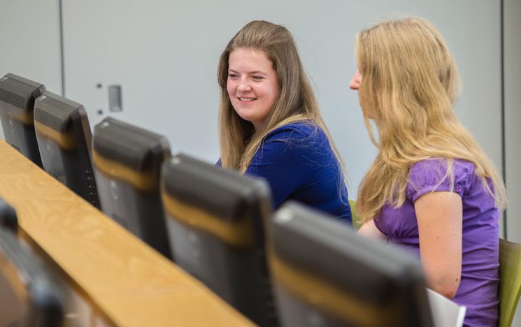 Two students sat at computer chatting