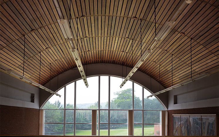 The wood-panelled roof of Mandela Hall in Falmer House, looking out through one of the famous arched windows.