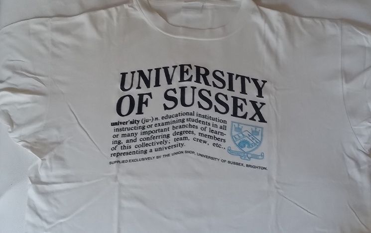 A white t-shirt which reads 'University of Sussex', with the dictionary definition of 'university' underneath.