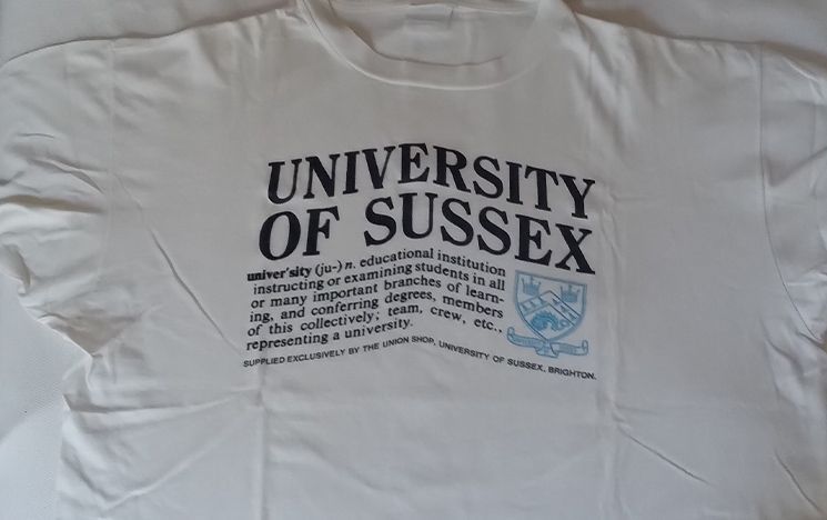 A white t-shirt which reads 'University of Sussex', with the dictionary definition of 'university' underneath.