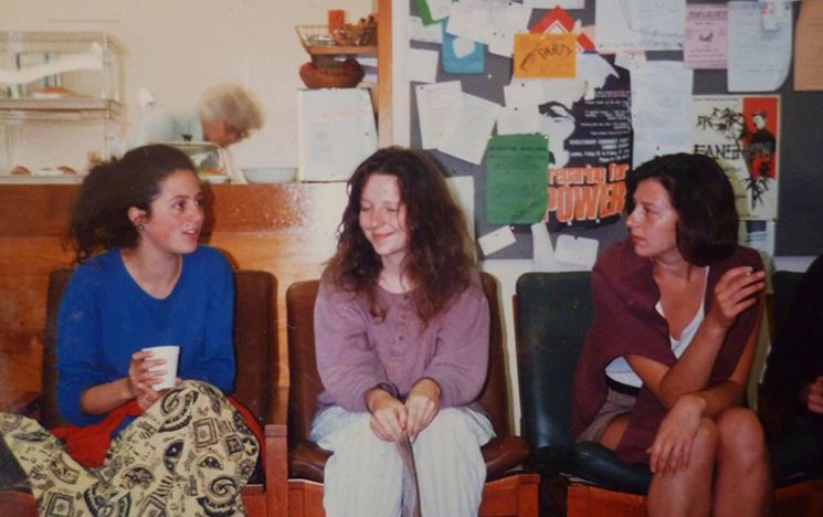 Three young women sit in a row, deep in conversation, in the AFRAS common room.