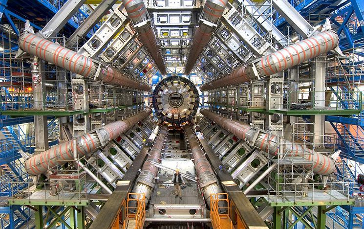 Person standing in large industrial machine with eight tubes and scaffolding