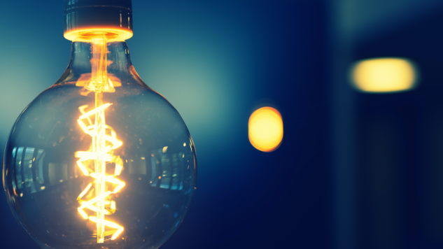 Image of lightbulb positioned to the left two lights in back ground to the lft, blue background