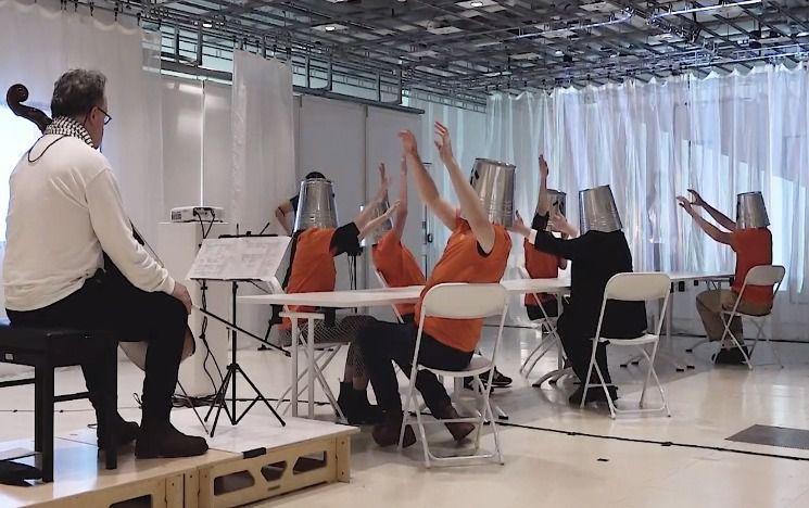 Cellist Anton Lukoszevieze with the Buckethead Chorus. Still from documentation by Catalina Balan.