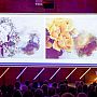 Alexandra Loske speaking on stage at Mondrian Lecture, with a large image of colourful flowers projected behind her. Image credit: Anne Reitsma