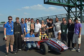 Formula Student Team pose with car on a race track.
