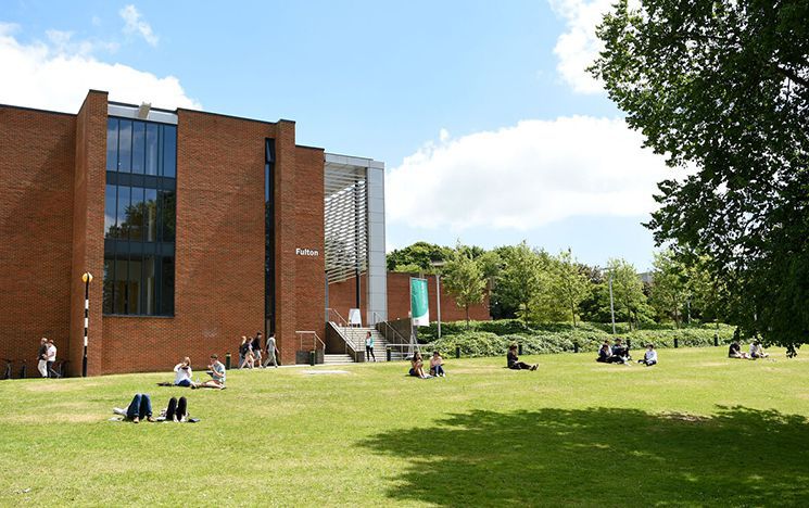Building with people sitting on grass in front 