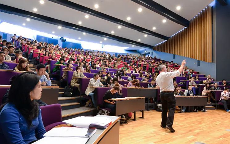 Lecture theatre with tiered seating full of people