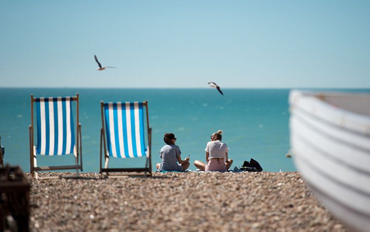 Deckchairs and people sitting on pebble beach