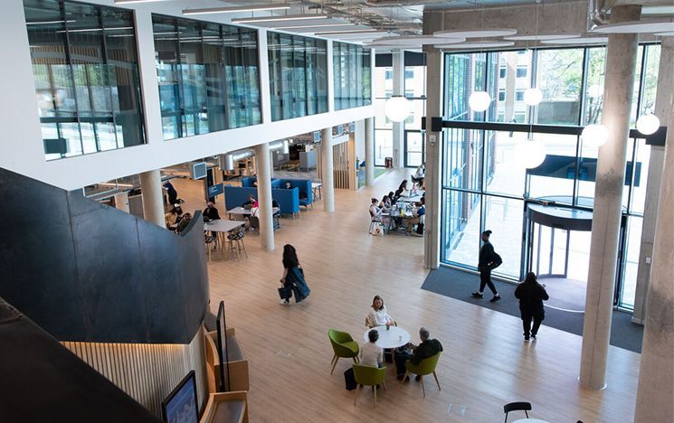 Top down view of the student centre foyer, with lots of people working on desks and walking around the open space.