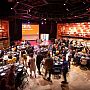 Top down view of an awards celebration in full swing at the ACCA, with busy, cabaret-style tables, balloons and the brightly lit acoustic wall panelling