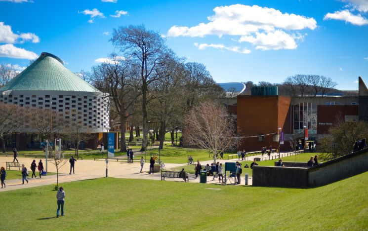 The Meeting House building with blue sky behind and grass in front at the University of Sussex