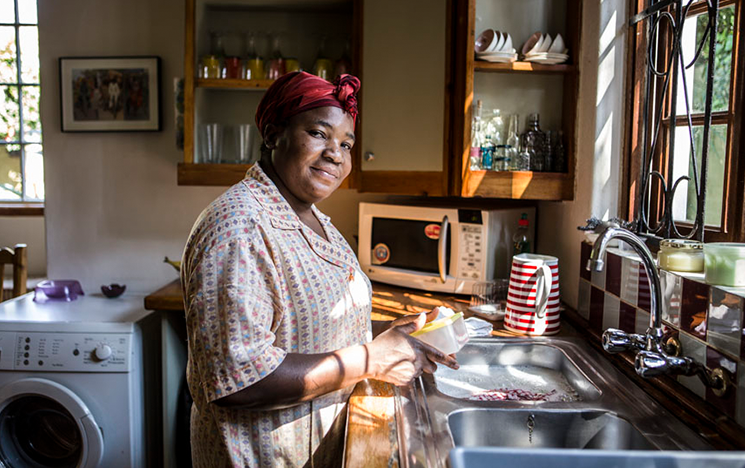 A woman standing at a kitchen sink washing up