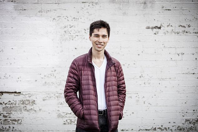 Alumnus Shin Suzuma standing in front of a white wall