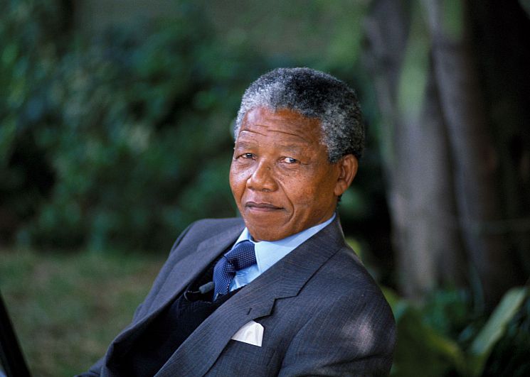 Nelson Mandela seated wearing a grey suit