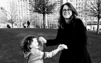 Black and white photo of Sarah-Jane and her daughter holding hands and dancing in a park