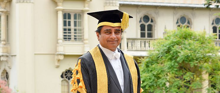 Sanjeev standing in front of The Dome building wearing his Chancellor's robes
