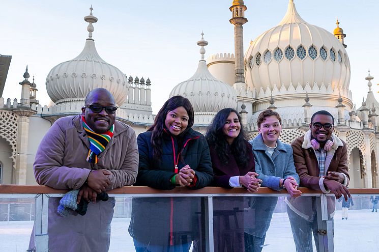 Five students standing together and smiling at the edge of the ice rink at the Royal Pavilion, Brighton