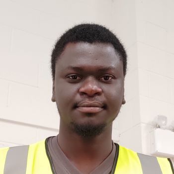 Segun standing and wearing high viz yellow vest
