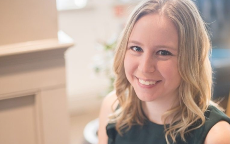 Head and shoulders photo of Anna Gregory-Hall, smiling, with home office background