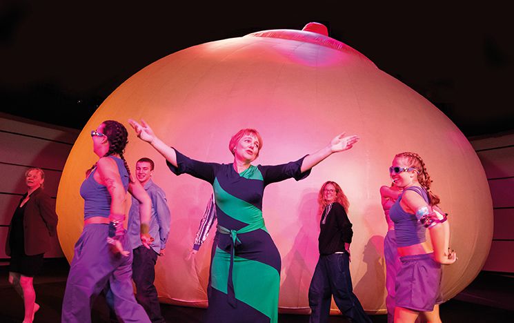 Prof Joanna Callaghan stands in front of the Big Breast installation with young dancers from Project Female