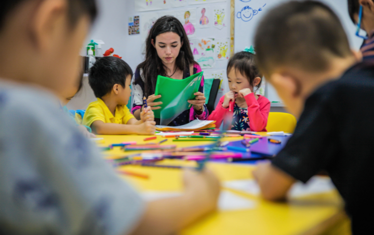 Brittany sat around a table covered in crayons teaching children in Singapore.