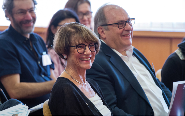 In the foreground of the photo are Virginia and Andrew Rudd sat down and smiling.