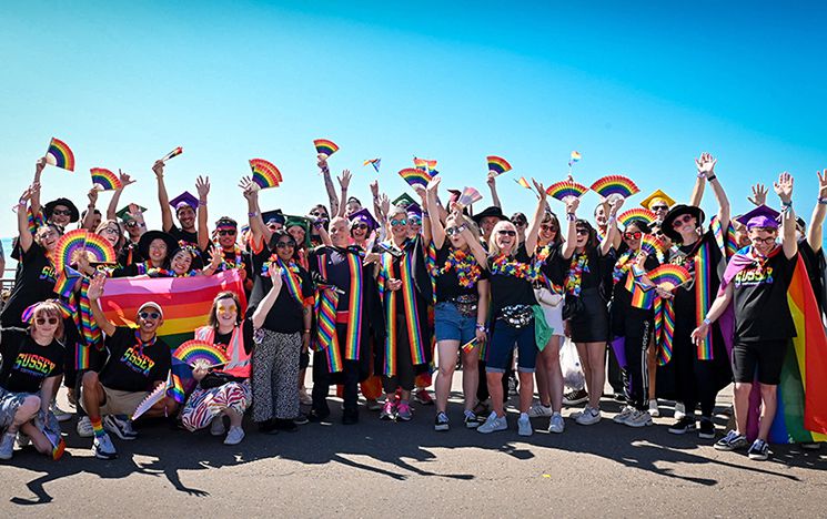 Staff, alumni and students dressed in rainbow colours on Brighton seafront at Brighton Pride
