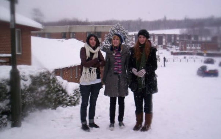 Lucy standing with two friends on a snowy day on campus.