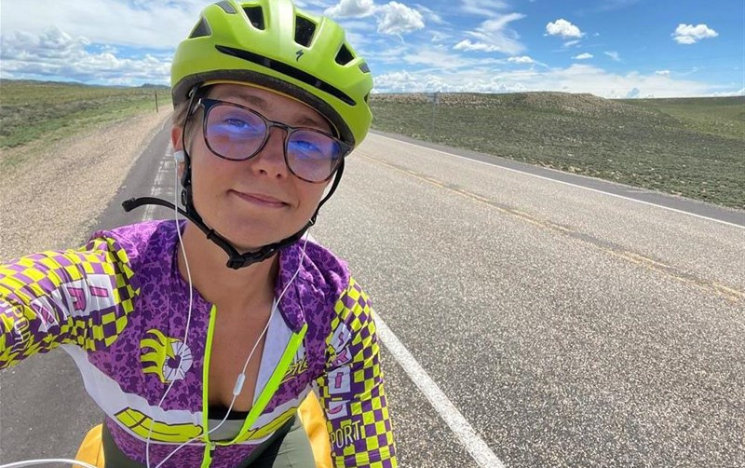 A selfie of Sarah Osborn cycling on the road in the US during their challenge.