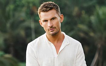 Alumnus Liam Hackett MBE in white shirt with green countryside background