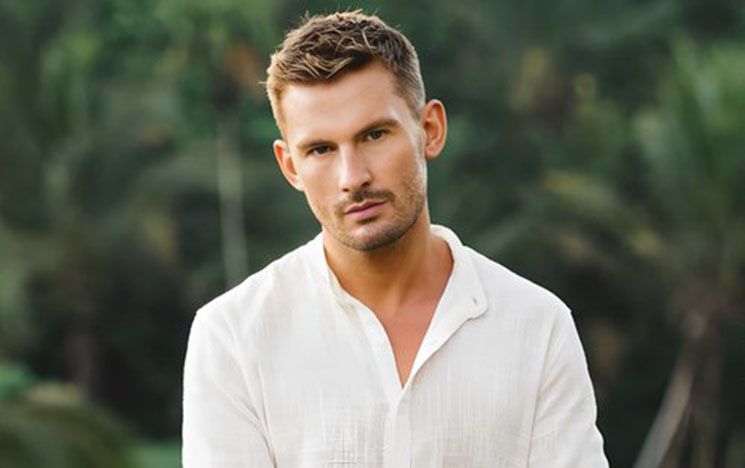 Alumnus Liam Hackett MBE in white shirt with green countryside background