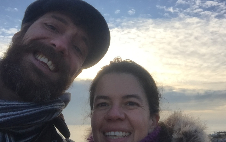 Jon McGlashan and Carolina Avellaneda smiling on the beach.