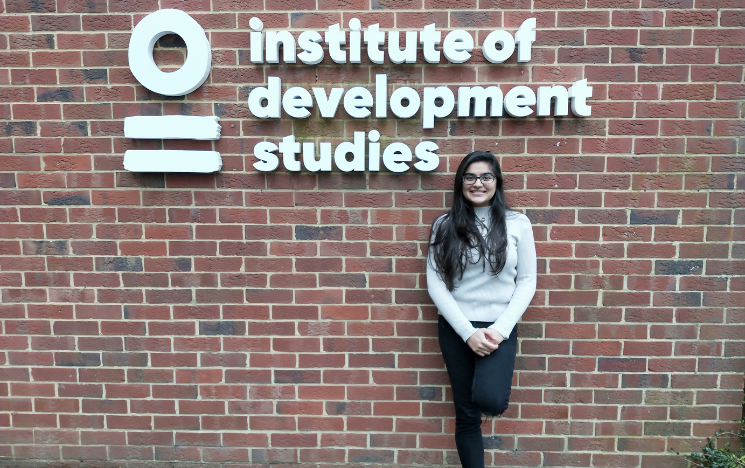 A student standing in front of a building on campus