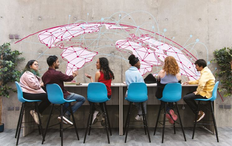 Students seated at long desk with globe wall decal behind them