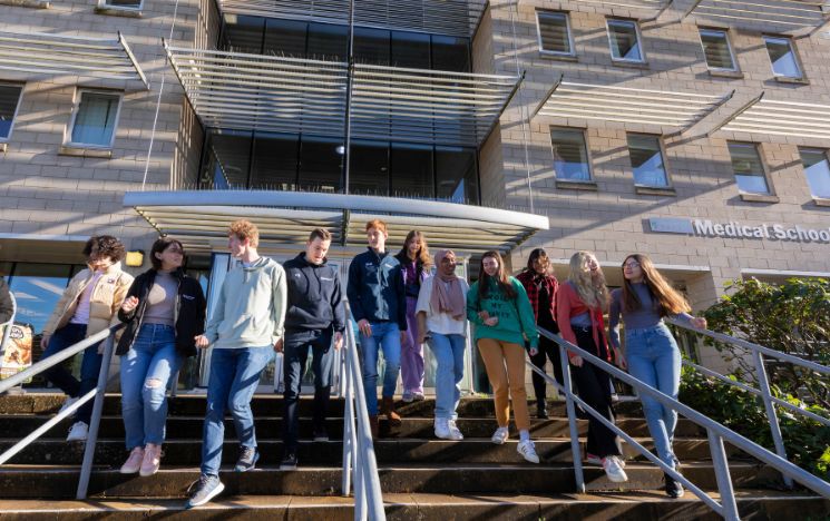 Group of students walking down steps in front of the Medical building on campus