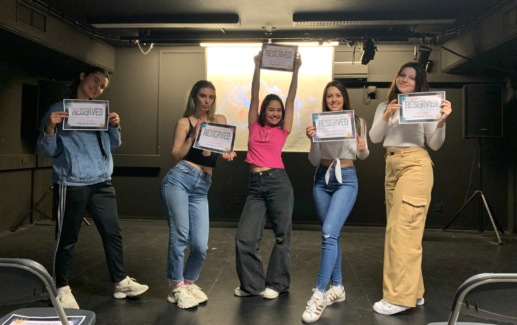 Rachel Nielsen with her fellow students posing with signs that read 'Reserved' in a dark room in front of a projector.