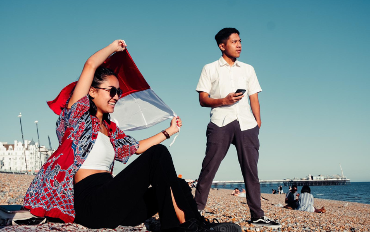 Rachel Nielsen posing on Brighton Beach with the Indonesian flag above her head.