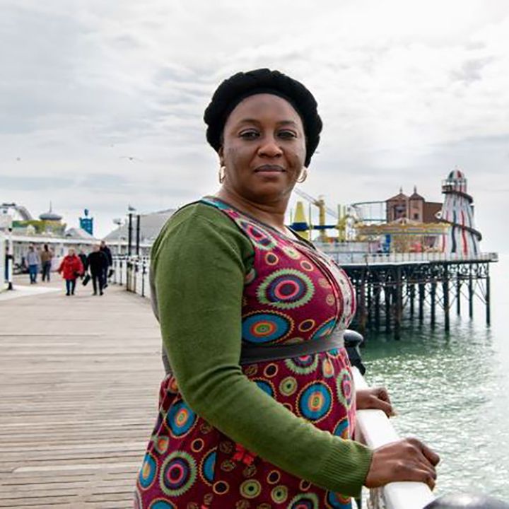 Awa Gaye Jeng, on the Palace Pier with the stripy helter skelter behind her