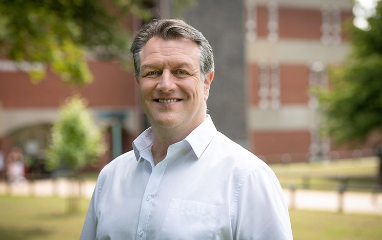 A man in a white shirt smiling at the camera