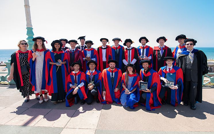 Group of people in academic robes in front of the sea