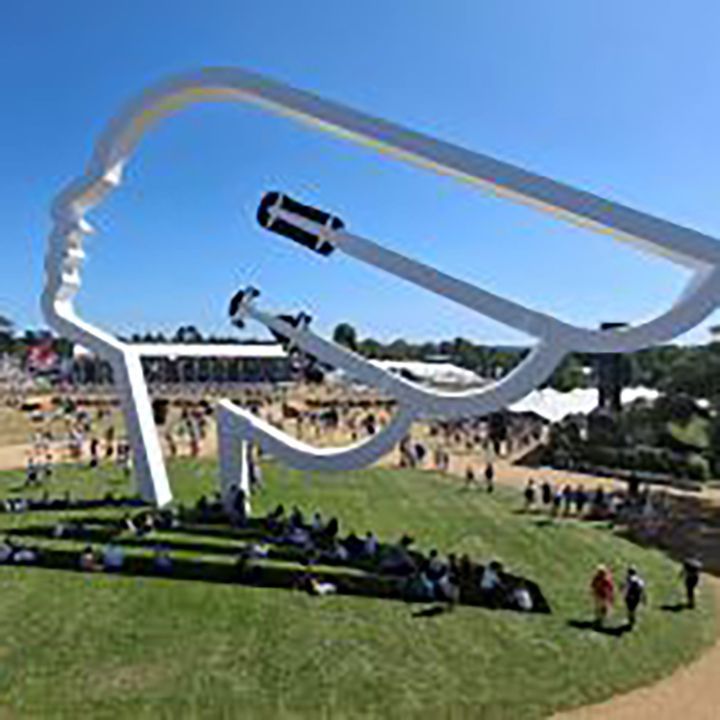 Large sculpture on grass with blue sky and crowd