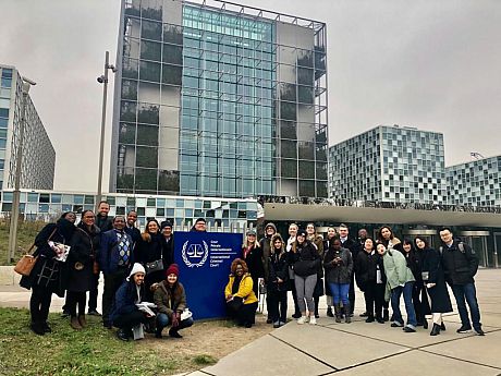 Group of students posing for photo crowded round the International Criminal Court sign