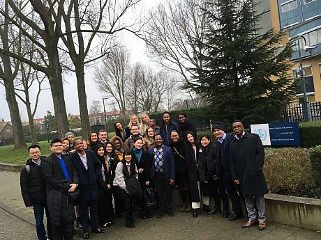 Group of students outside a building with tress in background posing for photo